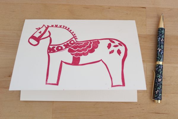 Pink Dala horse image on white card.